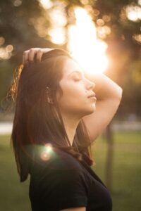 Profile of a woman enjoying the sunset with eyes closed, creating a peaceful ambiance.